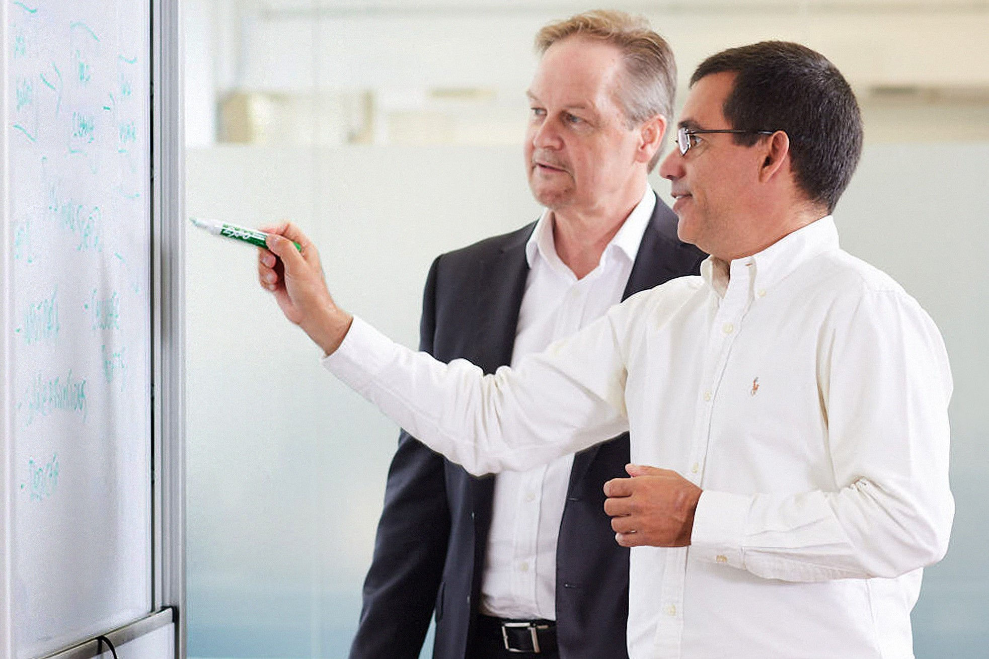 two-men-talking-while-writing-on-whiteboard