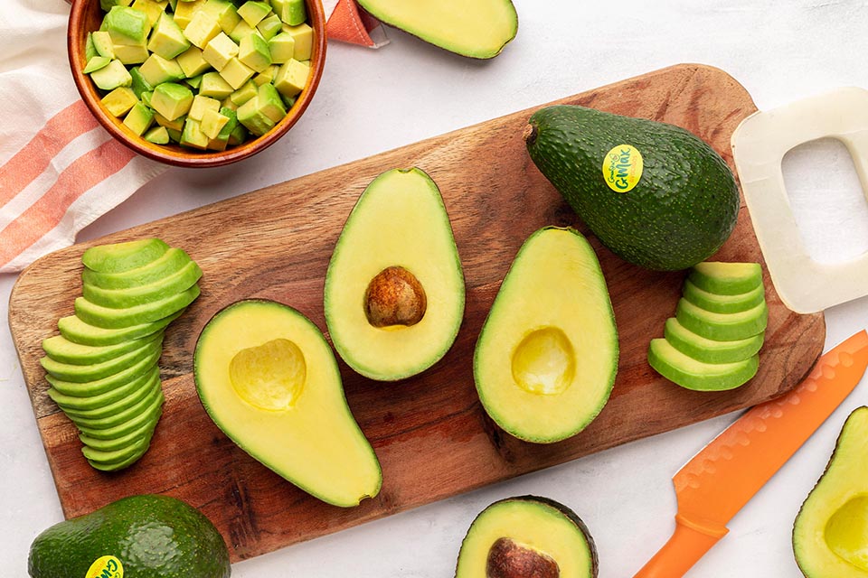 Various cuts of avocados displayed on a wooden serving board 