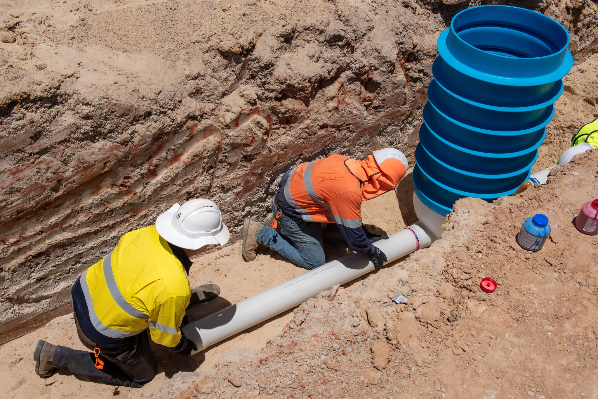 two-workers-installing-pipes-in-trench