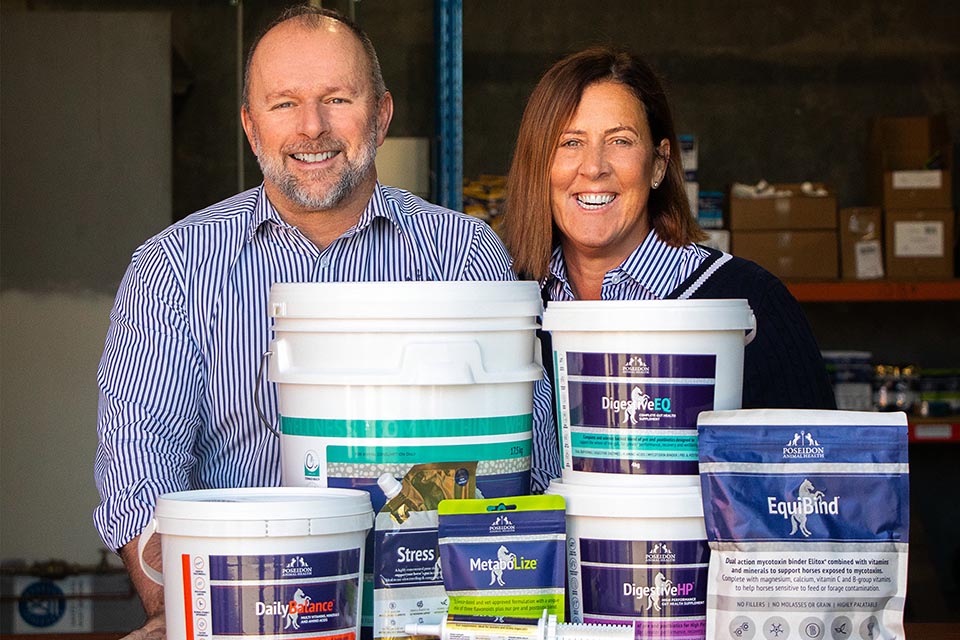 2 people with buckets and packages of horse and dog nutritional supplements