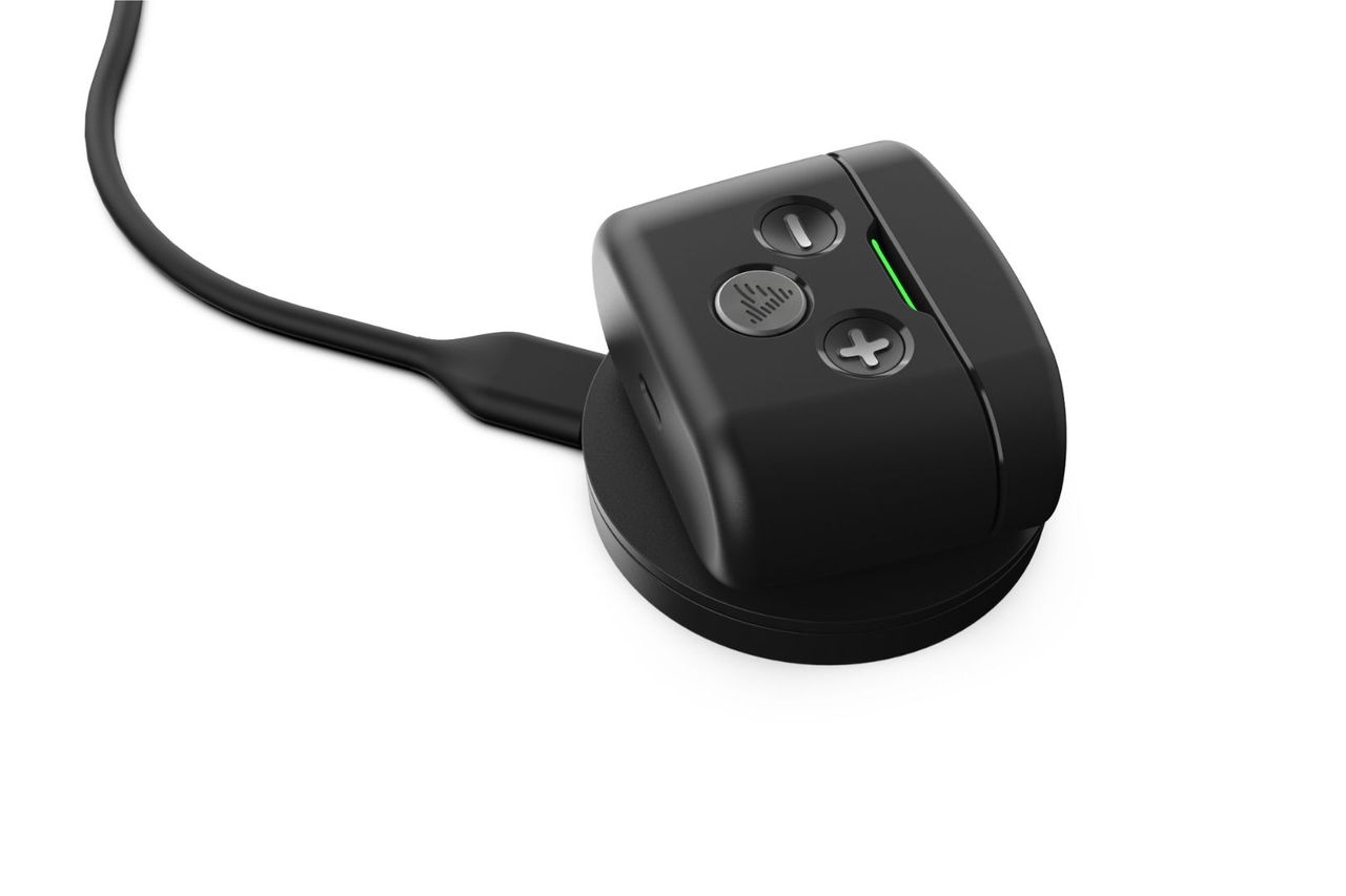 a black in-ear headset case sits on a wireless charging pad