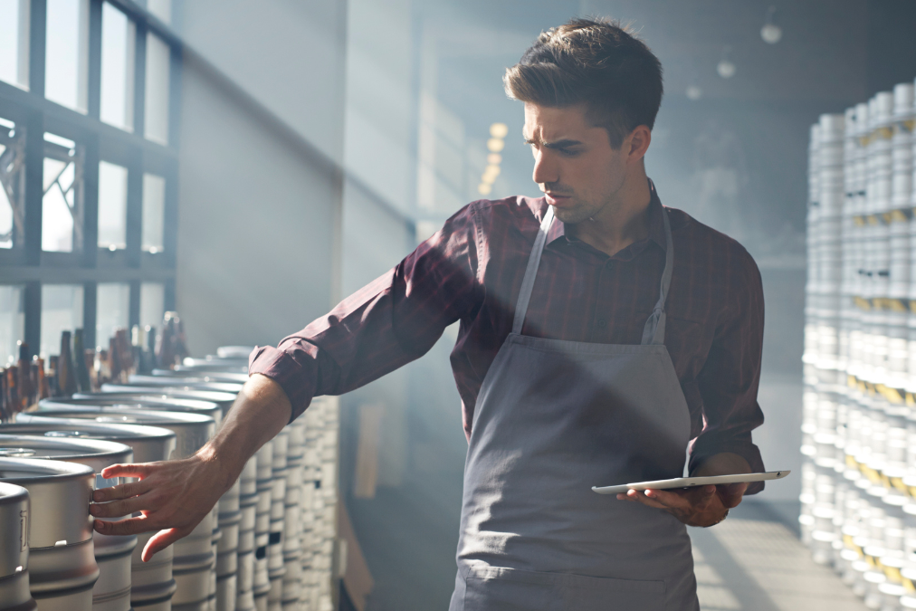 Man in apron looking at vats in a warehouse