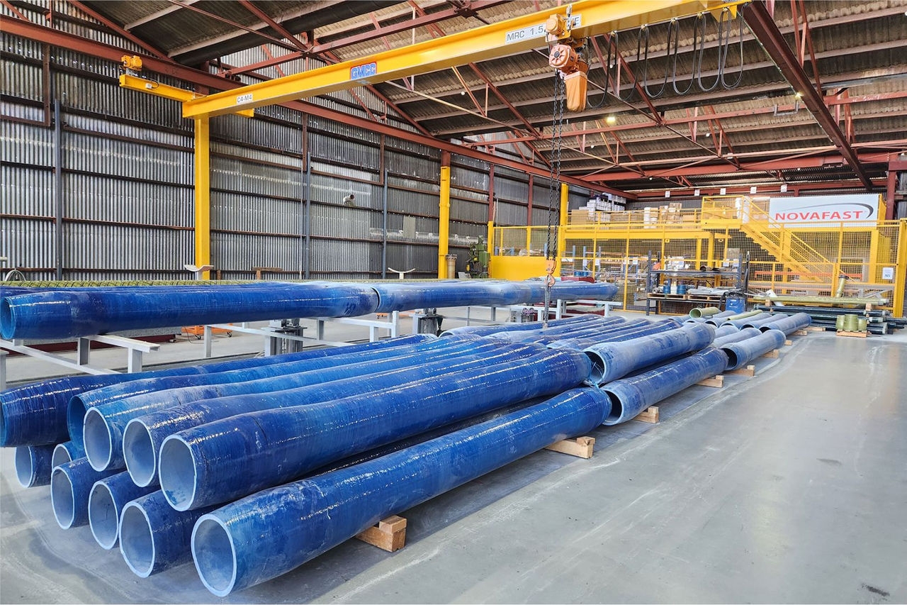 A collection of blue pipes stacked on a factory floor
