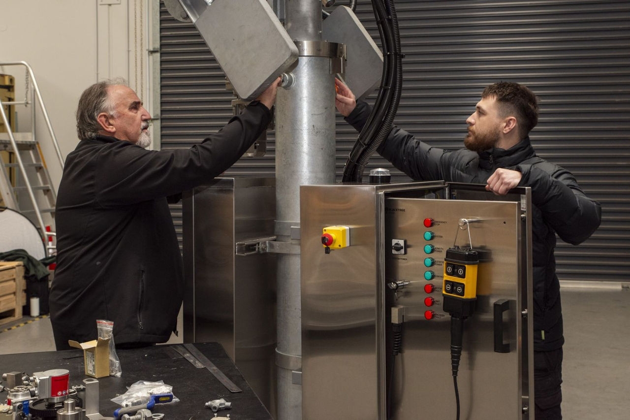 Two men working on a metal object in a workshop