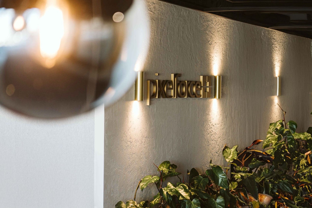 a external wall of a building with a sign lit up and shrubs growing at the base