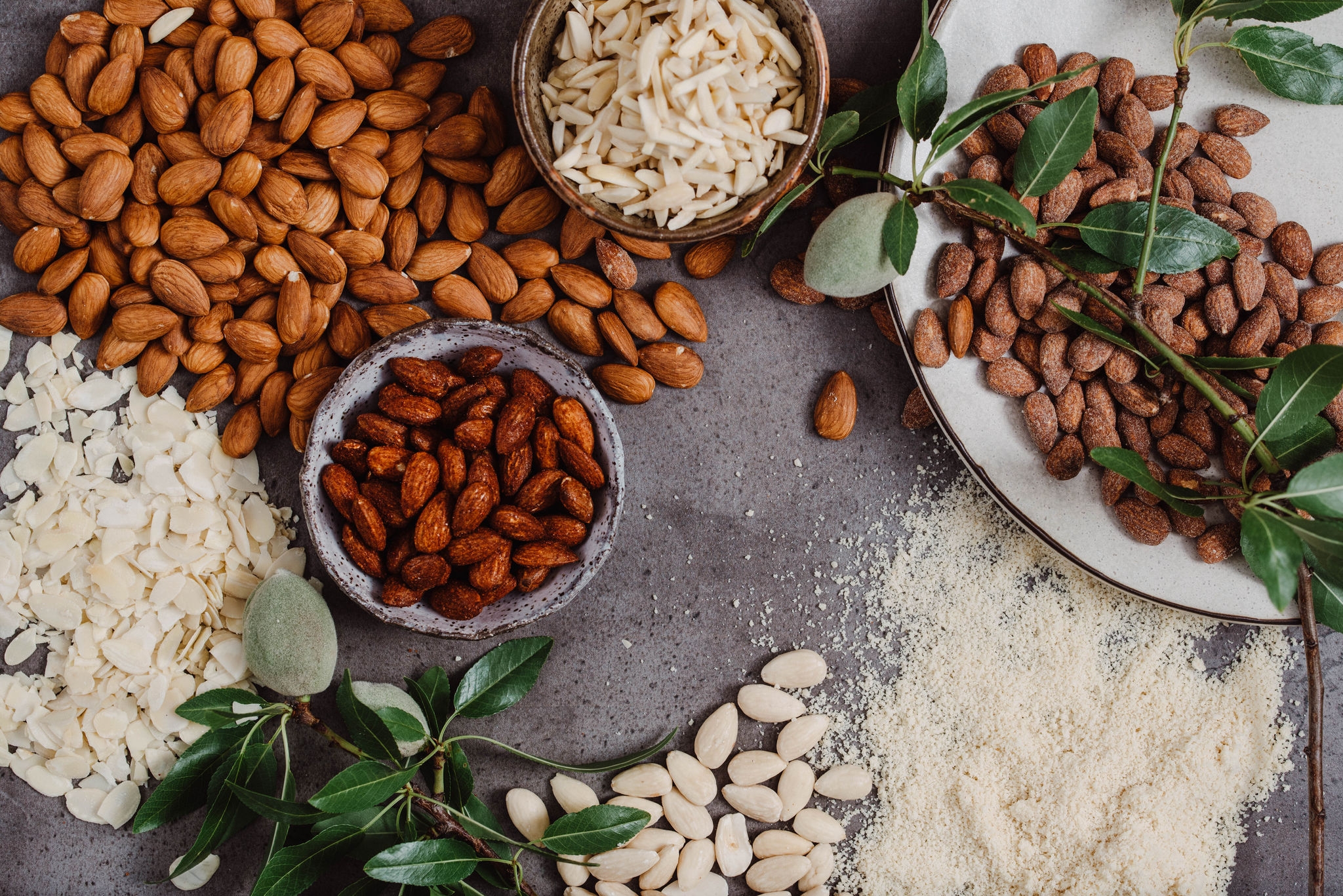 a-range-of-different-almonds-placed-across-a-table-granished-with-leaves