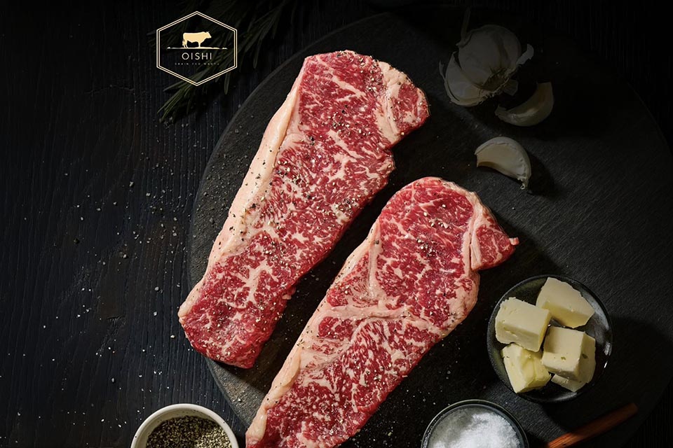 Two raw marbled steaks on a platter
