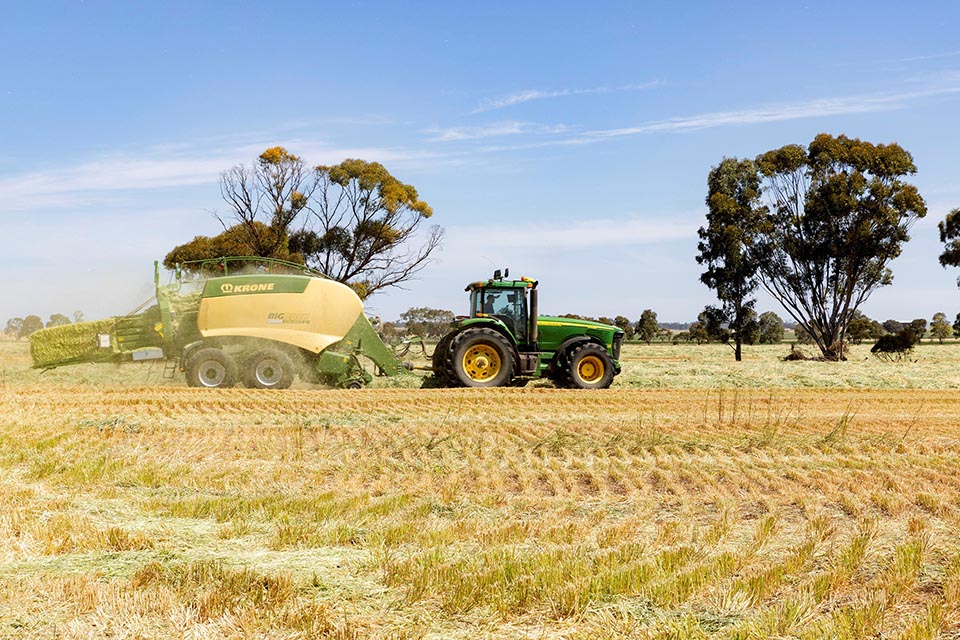 Tractor towing harvester on field of crops