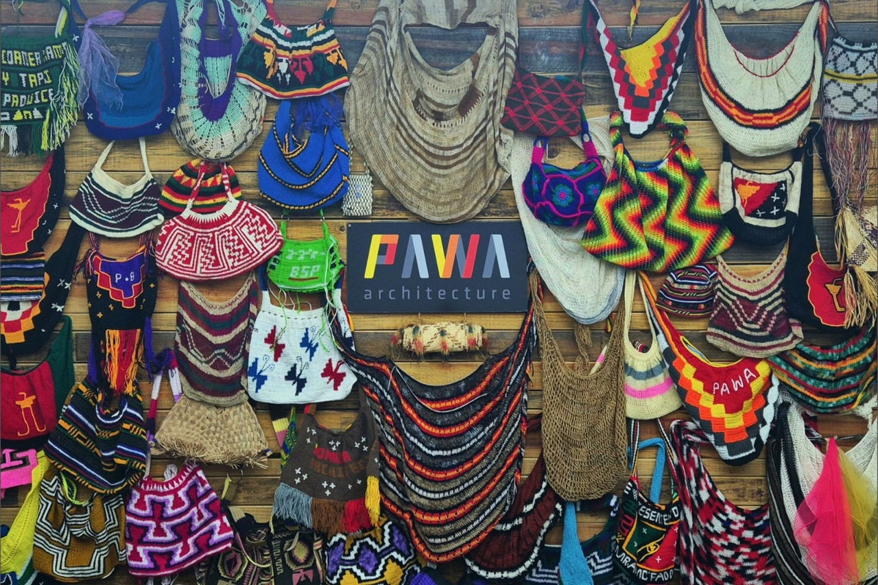 an range of handmade hats and bags hanging on a wall around the name of the company