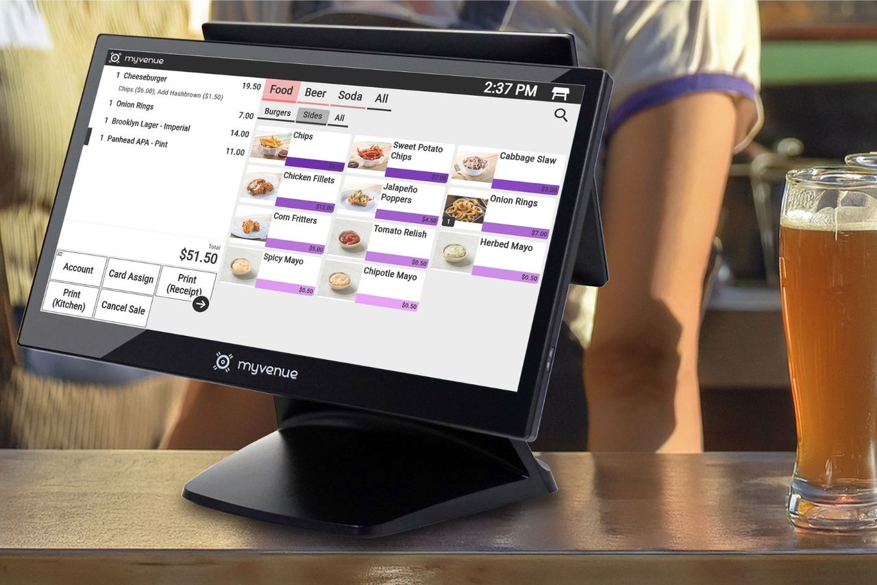 A fast food outlet point of sale computer display on a serving counter with a glass of beer alongside