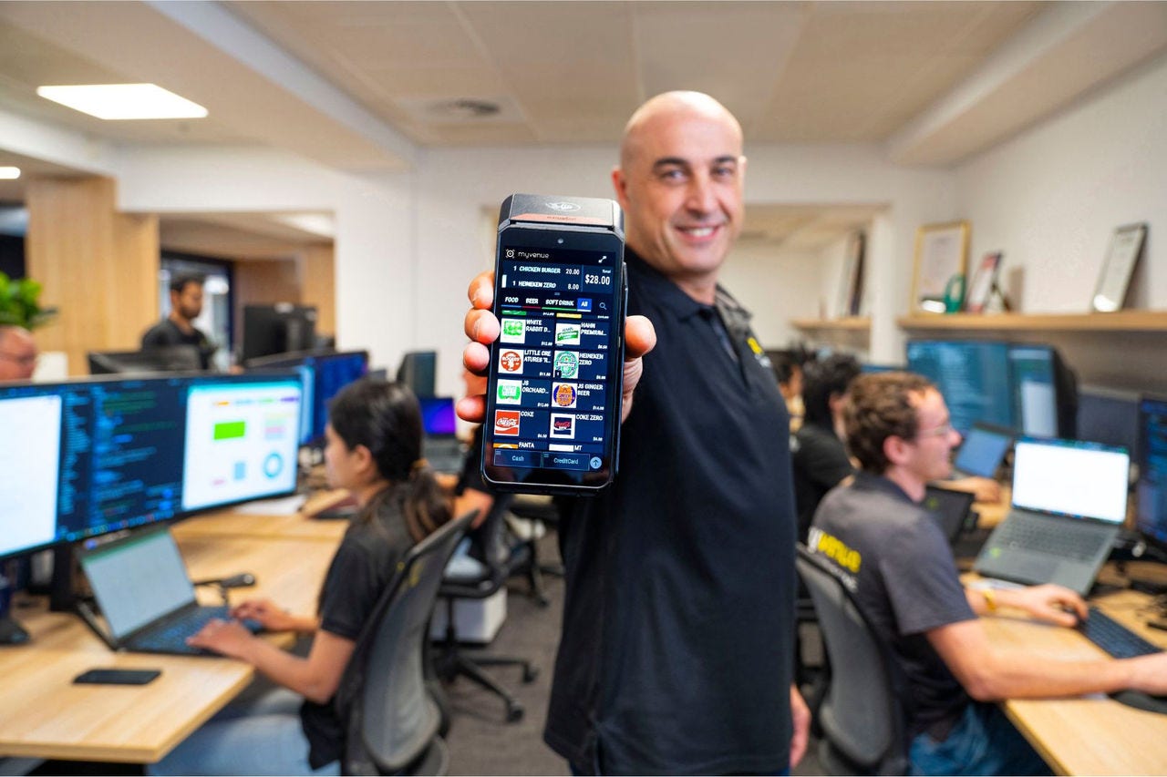 a point of sale screen list food items available for sale with a person standing behind the screen and a glass of beer positioned to the right