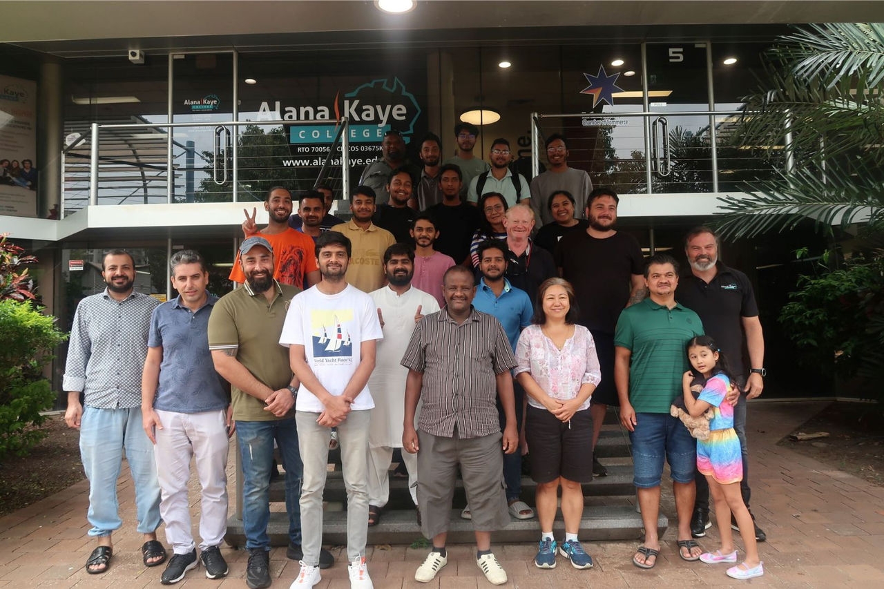 a group photo of men and women standing in front of a building