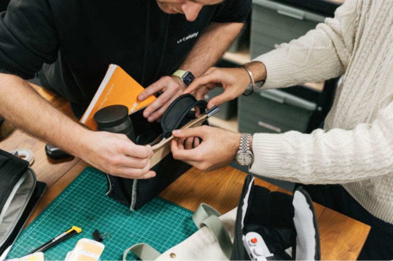 A male and a female are holding and inspecting an organiser bag on a manufacturing quality control table