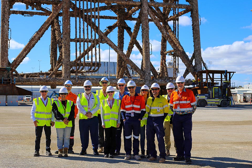 Group of workers on site with large, decommissioned frame