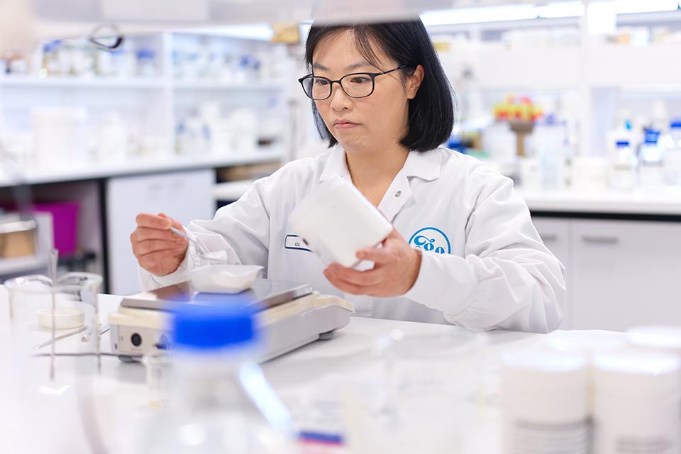 Woman in laboratory measuring quantities of ingredients.