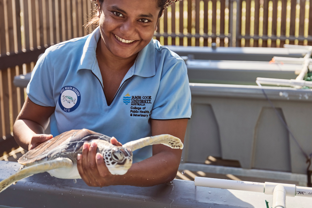 Woman in a trainee uniform holding a turtle at a wildlife partk