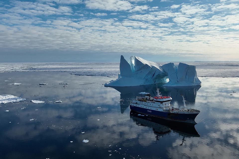 Fishing boat in calm sea with an iceberg in the background