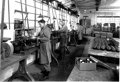 Historic photo of people working in factory making bowling balls