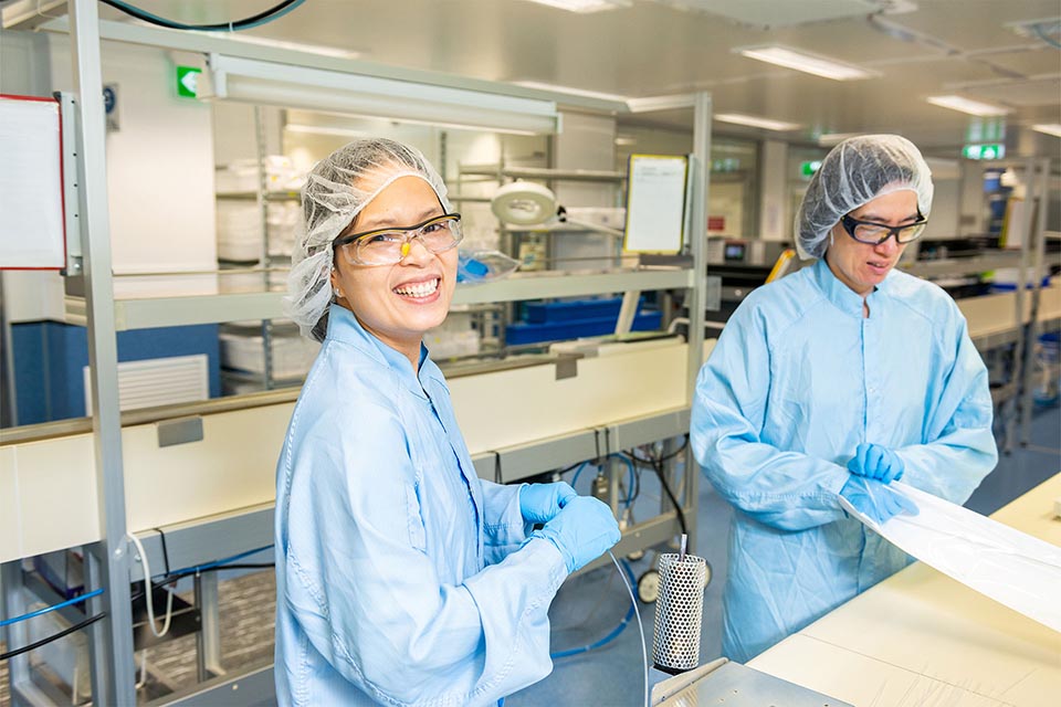 Two workers wearing blue protective clothing in laboratory