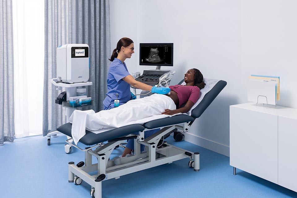 Patient laying on hospital bed with nurse conducting an ultrasound on her stomach